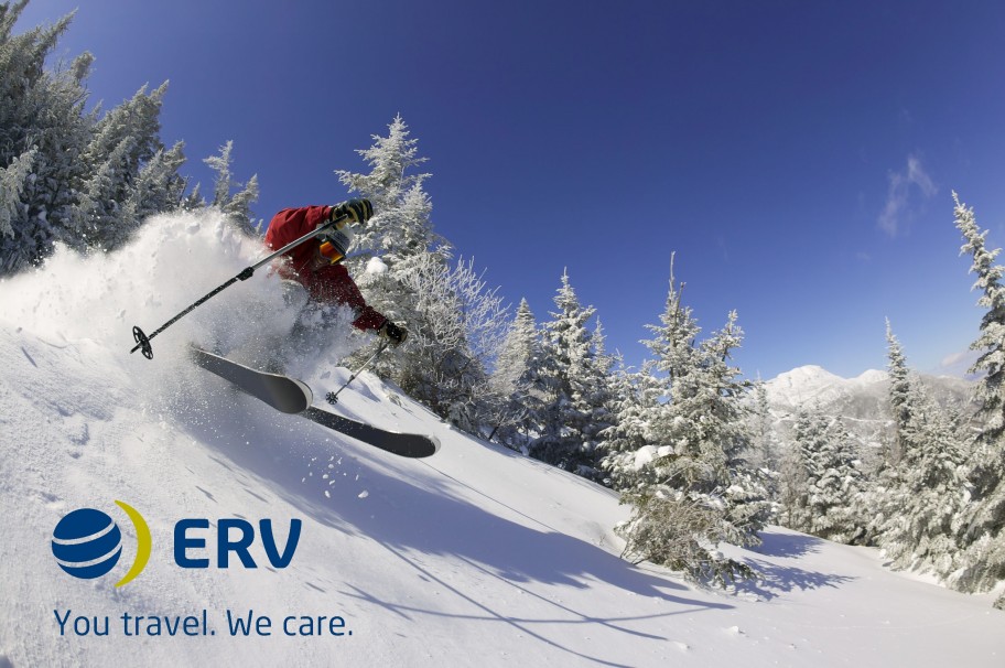 Skier skiing down snowy mountain surrounded by trees