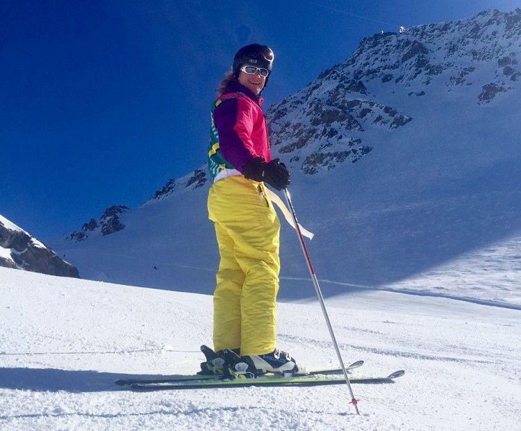 Skier posing on skis in front of snowy mountain