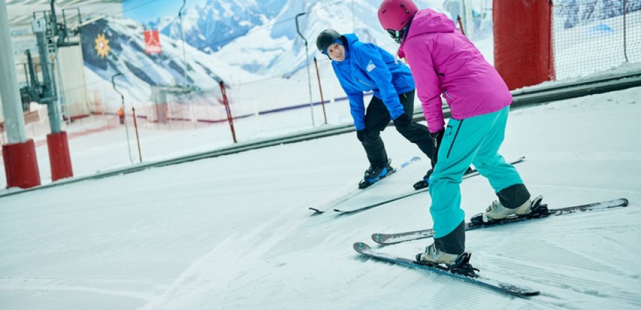 Instructor teaching someone to ski in an indoor slope near London