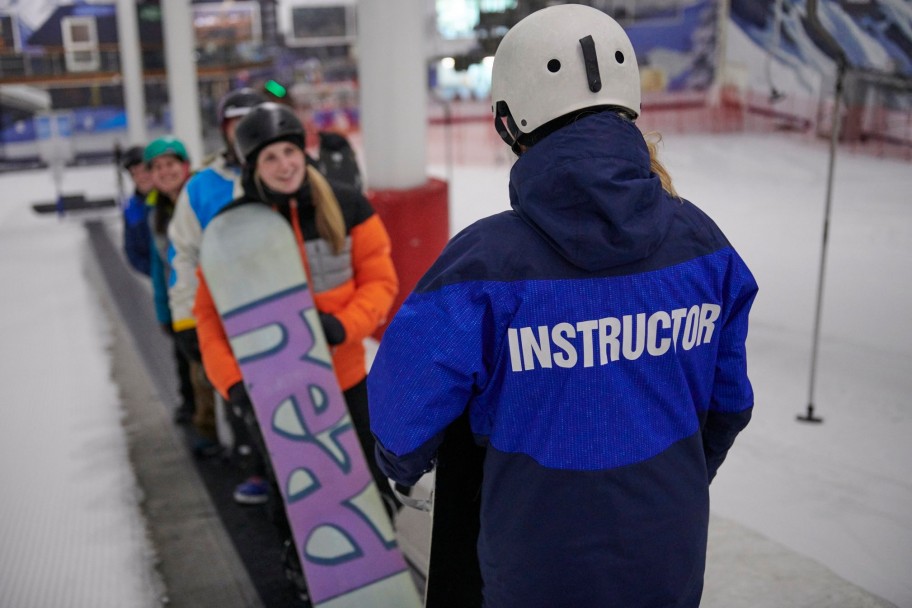 People being taught how to snowboard at an indoor ski slope near London