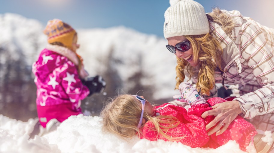 Mother and two young children playing in the snow