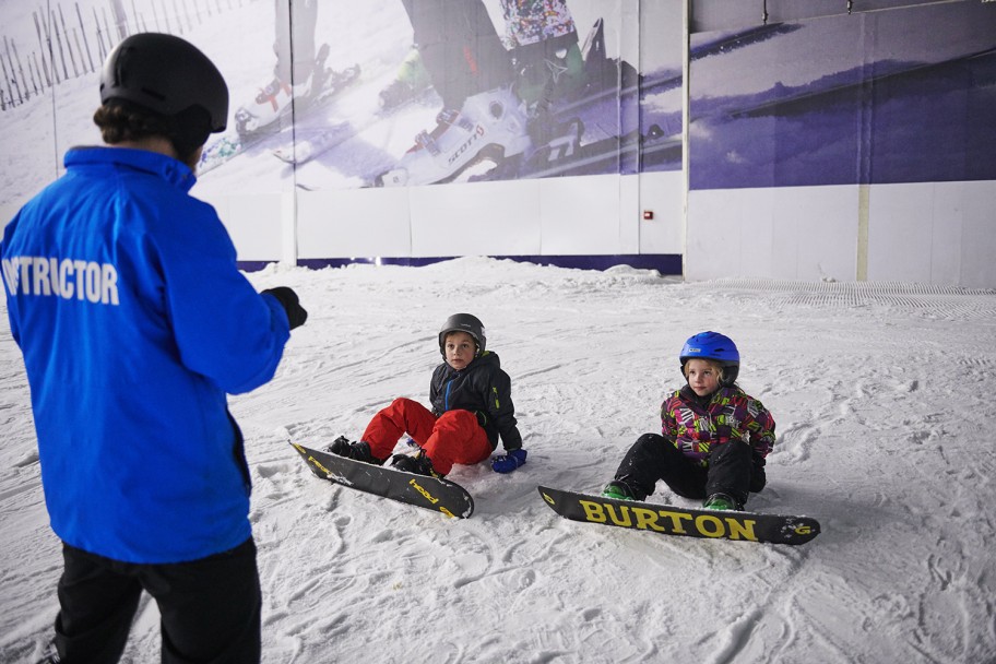 Snowboard instructor teaching two juniors in an indoor slope near London
