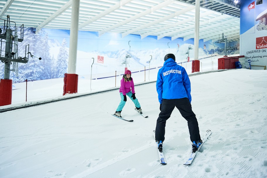 Instructor teaching someone to ski in an indoor slope near London