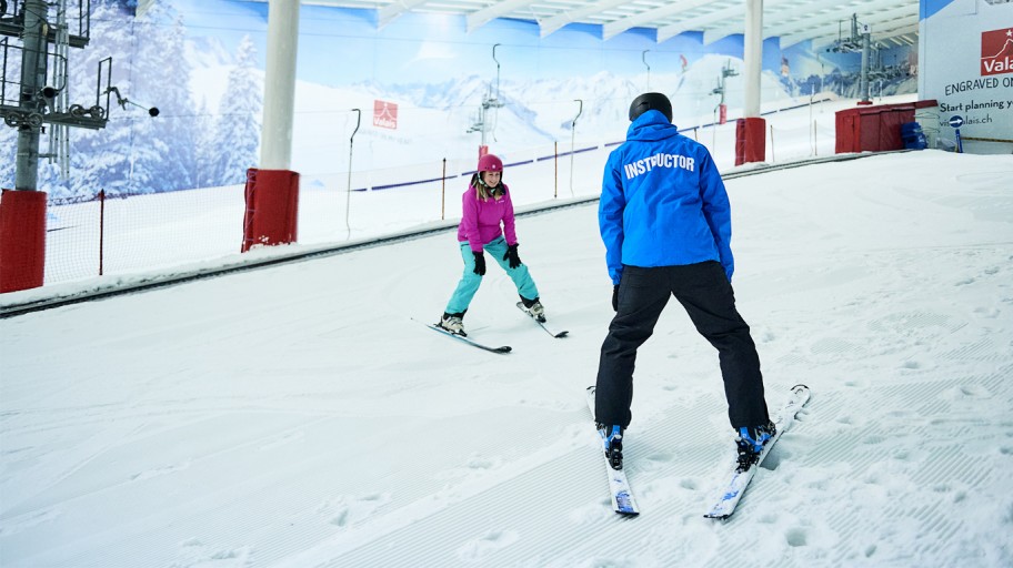 Instructor teaching someone to ski in an indoor slope near London