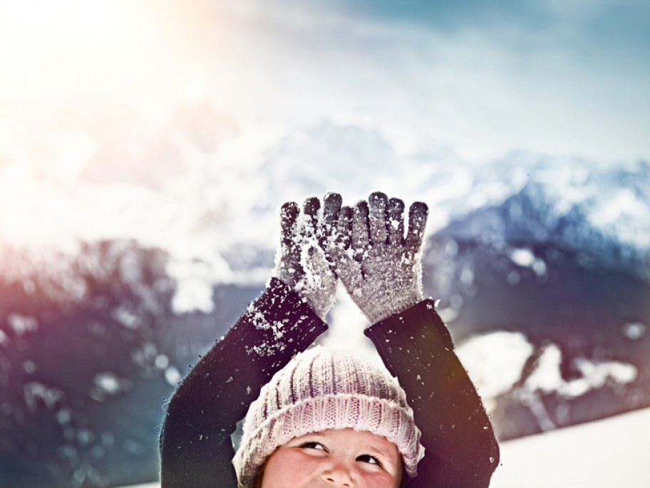 Child playing in the snow with hat and gloves on