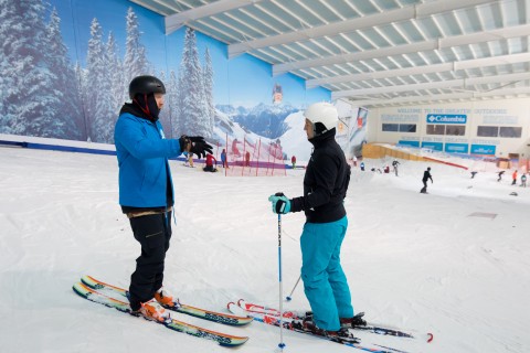 Ski instructor teaching another skier in an indoor slope near London