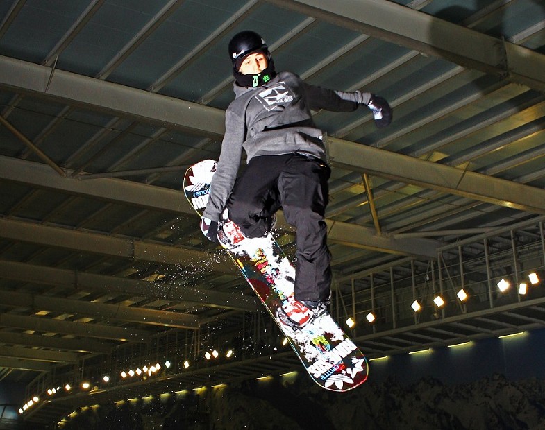 Snowboard freestyler in the air holding snowboard